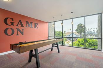 A pool table with the words "game on" on the wall behind it.